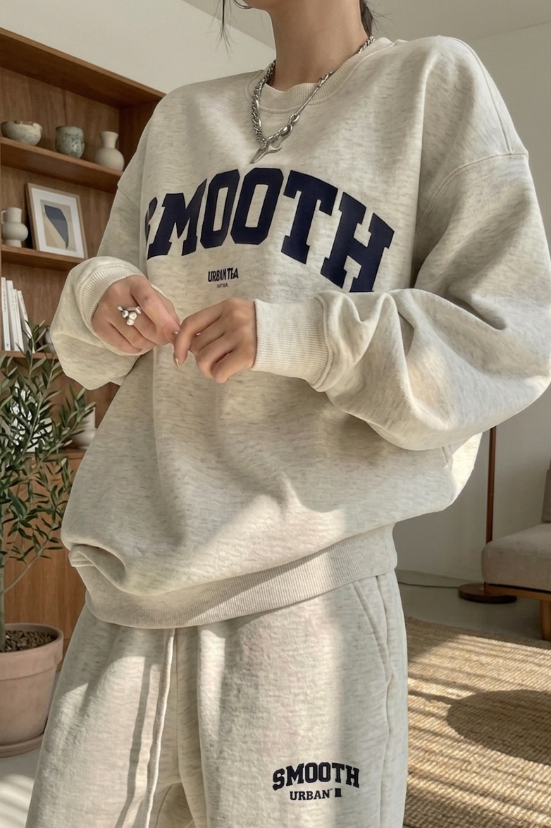Person wearing a gray 'SMOOTH' sweatshirt and pants in a home setting